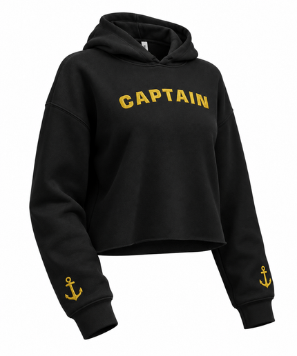 A black cropped hoodie sweatshirt with 'CAPTAIN' printed in yellow arched letters across the chest and a small yellow anchor graphic on each sleeve cuff, shown on a plain white background.