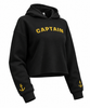 A black cropped hoodie sweatshirt with 'CAPTAIN' printed in yellow arched letters across the chest and a small yellow anchor graphic on each sleeve cuff, shown on a plain white background.